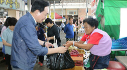추석 명절맞이 나주목사고을시장 장보기 행사 나주시장이 야채를 판매하시는 여성 상인분에게 물품을 구매하고 검은봉지로 전달 받고 있는 모습