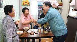 추석 명절맞이 공산5일시장 장보기 행사 나주시장이 5일장의 식당에서 식사를 하고 계시는 여성 어르신과 악수를 나누며 활짝 웃고 있는 모습