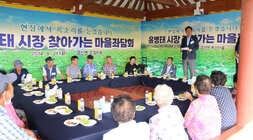 찾아가는 마을좌담회 마을 우산각에 남, 녀 어르신들이 직사각형 모양으로 둘러 앉아 있고 나주시장이 자리에 서서 인사말을 하고 있는 모습