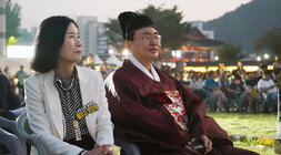 나주 문화유산 야행 나주시장이 관복을 입고 자리에 앉아 무대 위의 공연을 배우자와 함께 바라보고 있는 모습
