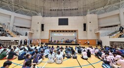 나주시배구협회장배 고등학교 남녀 배구대회 나주시장의 축사모습과 참석 선수들이 배구 코트 바닥에 앉아서 듣고 있는 뒷모습