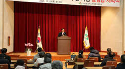 농촌지도자 나주시연합회 상징탑 제막식 나주시장의 축사모습과 참석자들의 앉아 있는 뒷모습 좌측면에서 촬영함