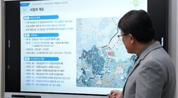 남성이 회의실 스크린에 투사된 지도를 가리키며 발표하고 있는 모습. 스크린에는 '노안 일반산업단지 조성사업 지정 및 개발계획 수립 용역' 관련 세부 내용과 추진 계획이 한국어로 표시되어 있다.