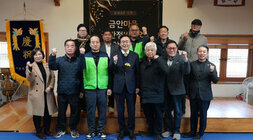 '금안마을 공간재생사업' 행사 참석자들이 무대 앞에서 단체 기념 촬영하는 모습. 10여 명의 남성과 여성이 카메라를 향해 주먹을 쥐거나 엄지손가락을 들며 포즈를 취하고 있다. 중앙의 남성(나주시장 윤병태)은 정장 차림이며, 일부 남성은 녹색 조끼를 착용하고 있다.