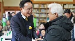 윤병태 나주시장이 한 노년 남성과 악수하며 환하게 웃는 모습. 주변에는 많은 참석자들이 테이블에 둘러앉아 있다.