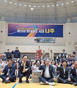 나주시배구협회장배 고등학교 남녀 배구대회 나주시장과 배구협회장 및 내빈들이  배구 코트 바닥에 앉아서 한손을 올리고 화이팅을 외치며 기념촬영을 하고 있는 모습