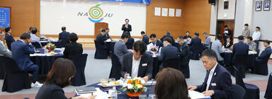 제2회 나주시 시정자문위원회 나주시장의 인사말 모습과 원형테이블에 앉아서 듣고 있는 자문위원들의 뒷모습