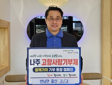 살기좋은 행복 나주 앞서가는 으뜸 나주 내고향 나주! 사랑하고 응원합니다. 나주시 고향사랑 기부 금 5,000,000원 함께 합니다. 같이 합니다. 반남면 출신 김문겸 이라고 적힌 팻말을 들고 있는 김문겸